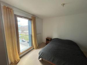 ein Schlafzimmer mit einem Bett und einem großen Fenster in der Unterkunft Spacious flat ideal for working or events in Boulogne-Billancourt