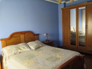 1 dormitorio con 1 cama con cabecero de madera y armario en K´María, en Pedrosa