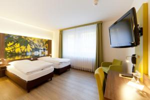 a hotel room with two beds and a flat screen tv at Waldhotel in Lingen