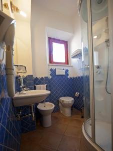 a blue tiled bathroom with a sink and a toilet at BUE MARINO Hotel-Restaurant-Cocktail Bar in Cala Gonone