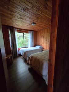 Cabaña 8 a 9 personas ideal 2 matrimonios y niños في كونياريبي: غرفة نوم بها سريرين ونافذة