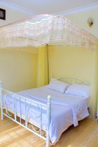 a white bed with a canopy in a bedroom at POPPI HOUSE 3 bedroom in Kampala +4 photos
