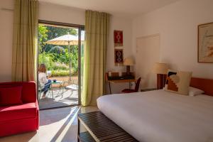 a bedroom with a bed and a woman sitting on a patio at Hôtel 96 in Marseille