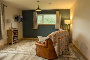 a living room with a chair and a window at Taigh Geal Apartment in Portree