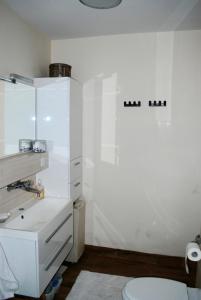 a white bathroom with a sink and a toilet at Homestay Kapitańska 9 in Gdynia