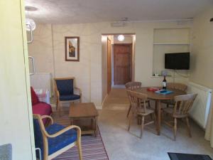 a living room with a table and chairs and a television at Penlan Farm Cottage in St Clears