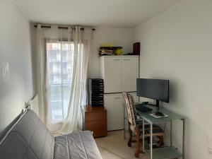 Zimmer mit einem Schreibtisch, einem Computer und einem Computermonitor in der Unterkunft Spacious flat ideal for working or events in Boulogne-Billancourt
