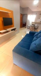 a living room with a blue couch and a tv at DUNAS RESIDENCE CASA 12 in Santo Amaro