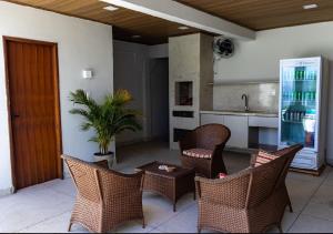 a living room with wicker chairs and a kitchen at Aconchego Dona Quita in São Miguel dos Milagres