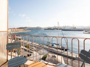 a balcony with chairs and a view of the water at Kratísti in Ermoupoli