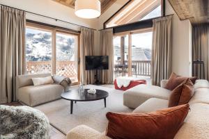 un soggiorno con un divano, sedie e un tavolo di Antarès MIRA 202 - Pretigious rooftop apartment ski inski out a Méribel