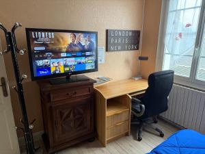 a room with a desk with a television and a desk with a chair at chambre d hotes chez josiane in Mayenne