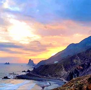 a sunset over the ocean with a beach and mountains at Casa Lucas tres in Almáciga