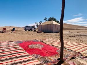 un tappeto sulla sabbia nel deserto di Nomads Life Style a M'Hamid