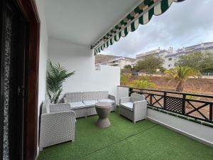 a balcony with a couch and chairs on a balcony at Ocean Light Apartment (100m from the beach) in Los Cristianos