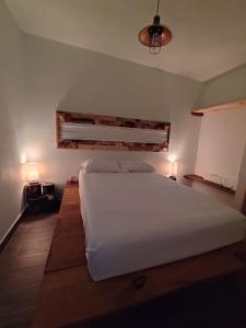 a bedroom with a large white bed and two lamps at Escondite Artesanal Mex in San Francisco Cuautliquixco