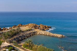 an aerial view of a beach with rocks and the ocean at Queens Bay Hotel in Paphos