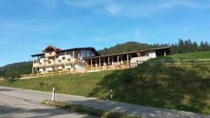 une grande maison sur une colline à côté d'une route dans l'établissement Haus Schwarzeck, à Ramsau bei Berchtesgaden