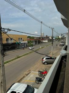 a view of a street with parked cars and motorcycles at Apartamento aconchegante no centro in Ariquemes