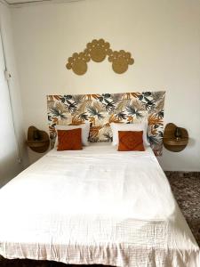 a bedroom with a white bed with orange pillows at Chambre Djaou meublée Voidjou in Batsa