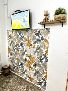 a tv on a wall with a floral wallpaper at Chambre Djaou meublée Voidjou in Batsa