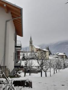 a building with a clock tower in the snow at Casa vacanze Monica in Campodenno +11 photos