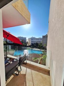 a balcony with two chairs and an umbrella and a pool at Appartement piscine front de mer in Mohammedia