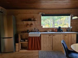 eine Küche mit Spüle und Fenster in einer Hütte in der Unterkunft Stuga Solros in Gräsmark