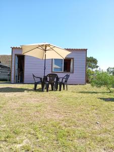 a table and chairs under an umbrella in a yard at Casa Violeta Punta del Diablo in Punta Del Diablo