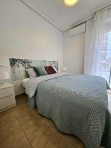 un dormitorio con una cama y una ventana en Bungalow Flamingo con terraza y playa, en Santa Pola