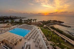 an aerial view of a resort with a swimming pool and the ocean at Queens Bay Hotel in Paphos