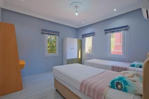 een blauwe slaapkamer met 2 bedden en 2 ramen bij Avci Villa-Fethiye 3+1 in Garden with Private Pool, 10 minutes to the beach in Fethiye +131 foto's
