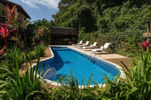 a swimming pool in a yard with chairs around it at Pousada Samambaia in Trancoso