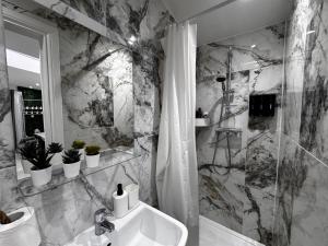 a marble bathroom with a sink and a shower at Modern One Bedroom Flat in Twickenham for Business Travelers in Hanworth +18 photos