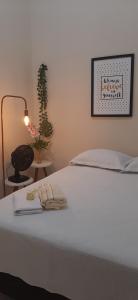 a bedroom with a white bed with a lamp and a plant at Quarto Casal 03 no Centro Histórico in São Luís
