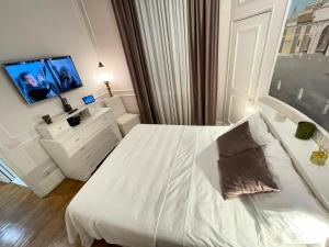 ein weißes Schlafzimmer mit einem Bett und einem Fernseher in der Unterkunft Dimora Vantaggio in Rom