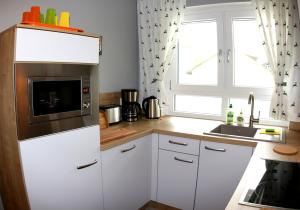 a kitchen with white cabinets and a microwave at Zugspitze City Center Apartment in Garmisch-Partenkirchen