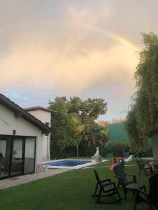 a rainbow over a yard with chairs and a pool at Like at Home Ezeiza in Ezeiza