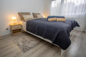 a bedroom with a bed with a blue comforter and a window at Apartman Park in Slavonski Brod
