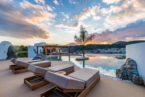 a house with a pool with lounge chairs and a sunset at Evlalia Studios & Villas in Skopelos Town