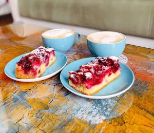 two pieces of cake on plates with two cups of coffee at Green in Negotin