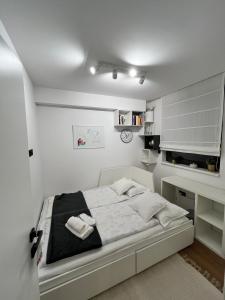 a white bedroom with a bed and a desk at Apartman Ingrid in Zaprešić