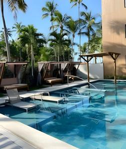 a swimming pool with chairs and palm trees at Amura - Beira mar de Carneiros in Tamandaré