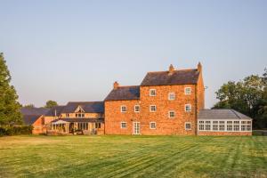 a large brick building with a large grass field at Hardwick Lodge in Wellingborough