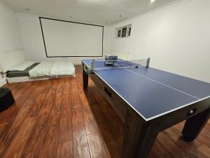 a ping pong table in a room with a screen at Large Annexe with games room pool table ping pong air hockey movie projector in Windsor +25 photos