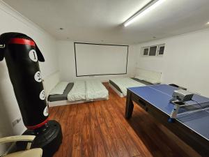 a room with two beds and a table and a white screen at Annexe with games room pool table ping pong air hockey movie projector in Windsor