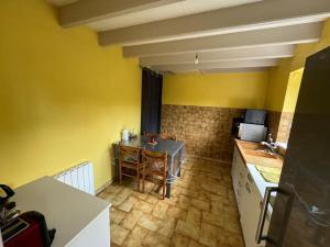 eine kleine Küche mit einem Tisch und eine Küche mit gelben Wänden in der Unterkunft Maison de campagne près du lac in Saint-Gelven + 5 Fotos