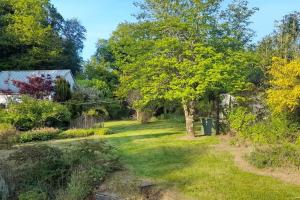 ein Garten mit einem Baum und einem Haus in der Unterkunft Maison de campagne près du lac in Saint-Gelven