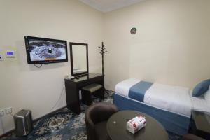 Cette chambre dispose d'un lit et d'une télévision murale. dans l'établissement فندق اضواء منازل الكرام, à La Mecque