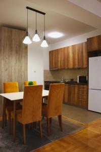 cocina con mesa, sillas y nevera blanca en S Apartment, en Skopje